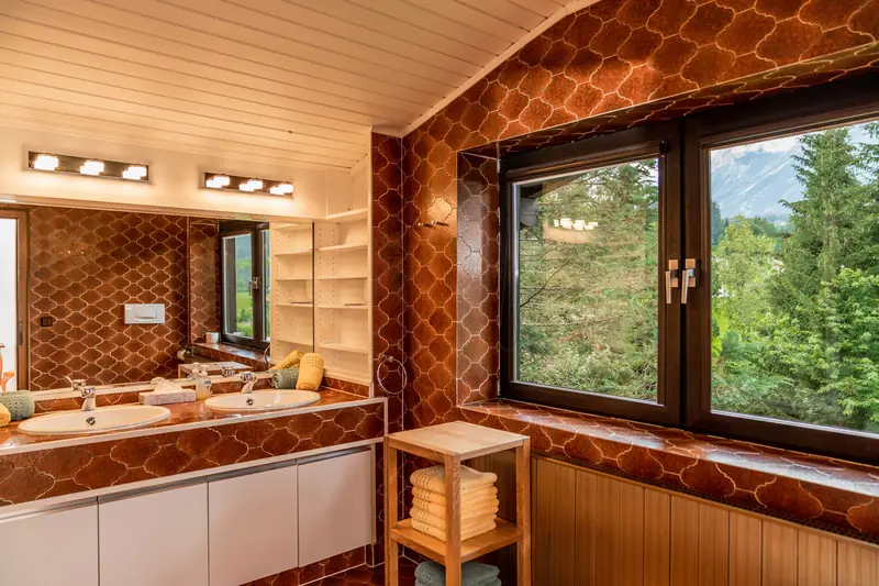 Badezimmer mit Waschtisch und Fenster in den Wald