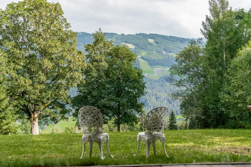 Zwei weiße Gartenstühle auf der Wiese mit Bergblick