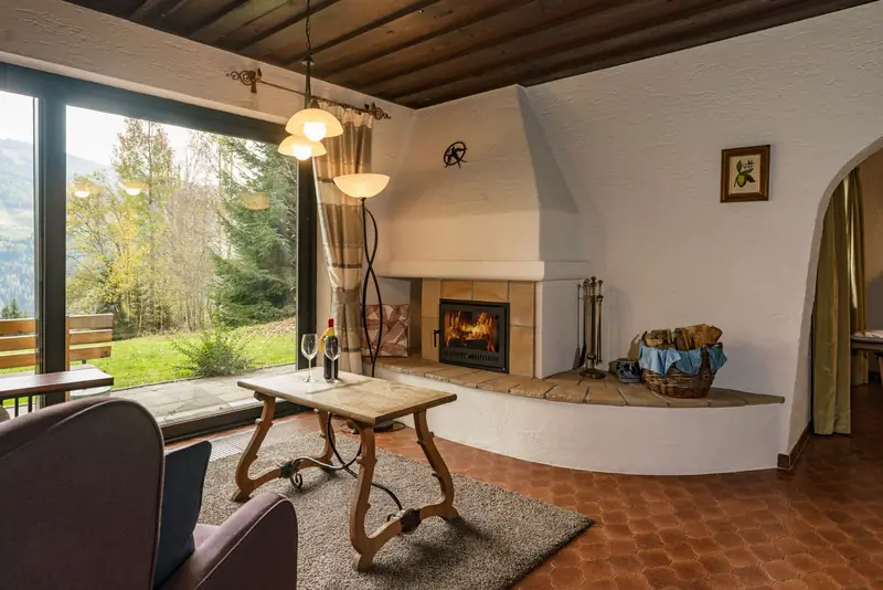 Wohnzimmer mit offenem Kamin, Ohrensesseln und großem Fenster zur Terrasse