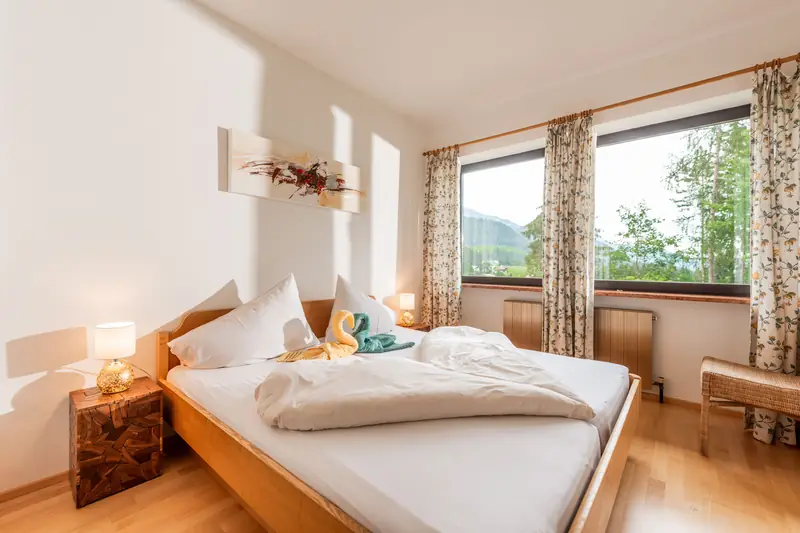 Schlafzimmer mit Holzbett und Blick ins Grüne