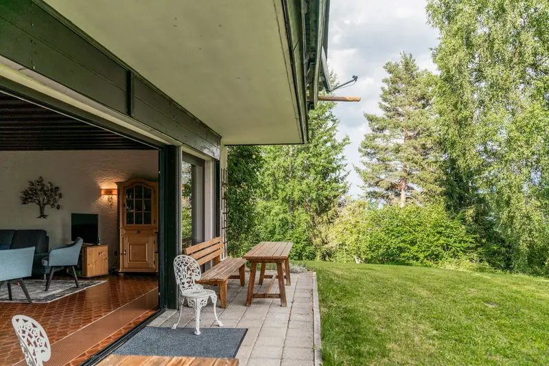Überdachte Terrasse mit Holzbank und Blick auf die Wiese